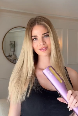 Mujer con cabello liso, suave y sin frizz después de alisarlo en casa